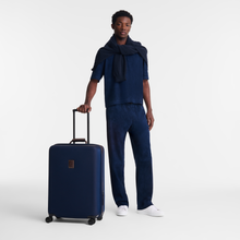 Load image into Gallery viewer, person standing next to a Longchamp Boxford Large Suitcase - Blue