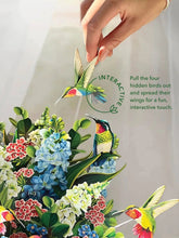 Load image into Gallery viewer, person touching on of the humming birds on the FreshCut Paper Hummingbird Oasis Pop-Up Greeting Card