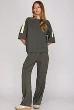 Load image into Gallery viewer, woman wearing charcoal gray pants and shirt with cream colors accents along the side of the sleeves and the side of the pants