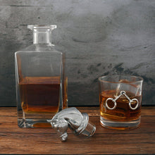 Load image into Gallery viewer, glass decanter with horse head shaped stopper and a glass with metal horse bit accents both filled with amber liquid