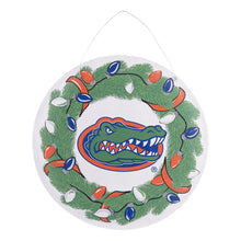 Load image into Gallery viewer, white disk printed with a green wreath decorated with orange blue and white light at the center of the wreath is the Florida Gator logo