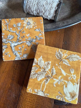Load image into Gallery viewer, two coasters with black and white bird and floral designs on a yellow background