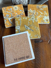 Load image into Gallery viewer, four coasters with black and white bird and floral designs on a yellow background one is turned over to show the underside with a cork backing