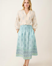 Load image into Gallery viewer, woman wearing the Estelle Midi Skirt Lightner Camellia Blue with her hands in the side pockets