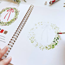 Load image into Gallery viewer, Christmas Watercolor Workbook with a person painting wreath