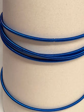 Load image into Gallery viewer, Coiled blue cable on a beige background