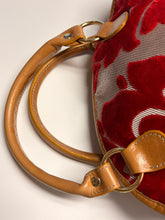Load image into Gallery viewer, Close-up of a red floral bag with brown leather handle and strap on a light background