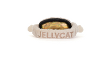 Load image into Gallery viewer, A plush pet headband featuring the name 'JELLYCAT' embroidered in light pink on a cream-colored fuzzy band, with a gold iridescent shell insert and a black inner lining.