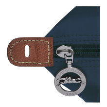 Load image into Gallery viewer, Person carrying Longchamp Le Pliage Original Large Luggage Travel Bag in navy - close up of zipper pull with Longchamp logo