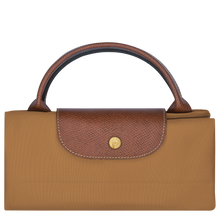 Load image into Gallery viewer, person holding the Longchamp Le Pliage Original X-Large Travel Bag in fawn folded and snapped closed