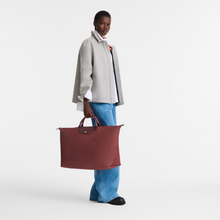 Load image into Gallery viewer, Person holding a Longchamp Le Pliage Green X-Large Canvas Travel Bag in Pomegranate