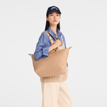 Load image into Gallery viewer, person holding the Longchamp Le Pliage One L Shoulder Bag Handbag in beige under her shoulder