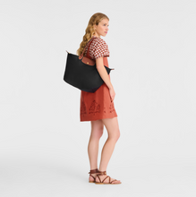 Load image into Gallery viewer, person with Le Pliage Original Large Shoulder Tote Bag in the color black carrying with handle resting on her shoulder