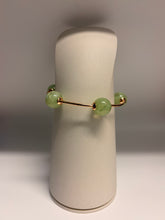 Load image into Gallery viewer, Green beaded earring on a white stand against a gray background