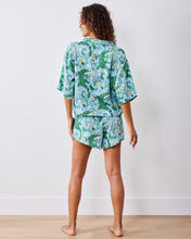 Load image into Gallery viewer, woman in the Printfresh Gator Grove Eco Satin Sweet Dreams Set in Blue Lagoon short sleeve button down top and short shorts back view