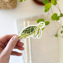 Load image into Gallery viewer, hand holding a Green Sea Turtle Sticker in a watercolor style