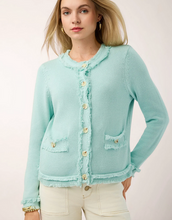 Load image into Gallery viewer, A woman wearing a light mint green fringed cardigan with gold buttons, paired with cream pants, against a plain light background.