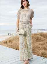 Load image into Gallery viewer, Woman standing on a wooden boardwalk by the beach wearing a patterned outfit.