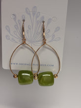 Load image into Gallery viewer, Gold hoop earrings with green beads on a white card with branding.