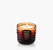 Load image into Gallery viewer, A lit Voluspa Fender Midnight Leather scented candle in a ribbed amber glass jar, set against a clean white background.