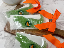 Load image into Gallery viewer, green gummy candy in packaging tied with an orang bow on a cutting board