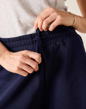 Load image into Gallery viewer, close up of hands tying the drawstring a the waist of the Mersea Frenchie Pajamas Shorts in blue