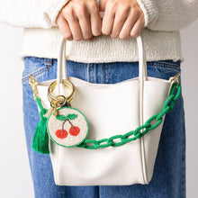 Load image into Gallery viewer, person holding a white bag with the Kelsey Cherries Seed Bead Bag Accessory Key Ring clipped to one of the handles