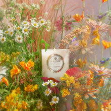 Load image into Gallery viewer, Voluspa Wildflowers Classic Candle in white jar sitting in flowers