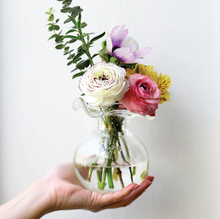Load image into Gallery viewer, Vietri Hibiscus Clear Glass Bud Vase with flowers sitting on the palm of a persons hand