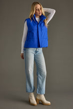 Load image into Gallery viewer, woman in a puffy Classic royal blue Vest paired with a black shirt and jeans with the vest zipped closed
