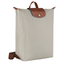 Load image into Gallery viewer, Longchamp Le Pliage Original Backpack - Medium in Pebble gray with brown leather straps and center flap and gold snaps and zipper pull side view to show width
