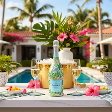 Load image into Gallery viewer, Champagne Bottle covered with the Verde Palm Pavilion Prosecco Bottle Wrap on a table set for a summer party
