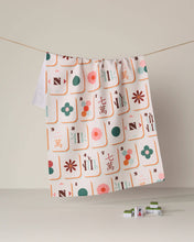 Load image into Gallery viewer, Geometry Cypress Tile Toss Tea Towel - Mahjong handing from twine with a stack of clean dishes next to it
