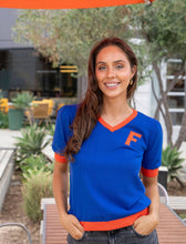 Load image into Gallery viewer, Blue short sleeve sweater with orange hems and neckline with an orange F over the heart
