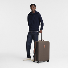 Load image into Gallery viewer, person standing next to a Longchamp Boxford Large Suitcase - Brown
