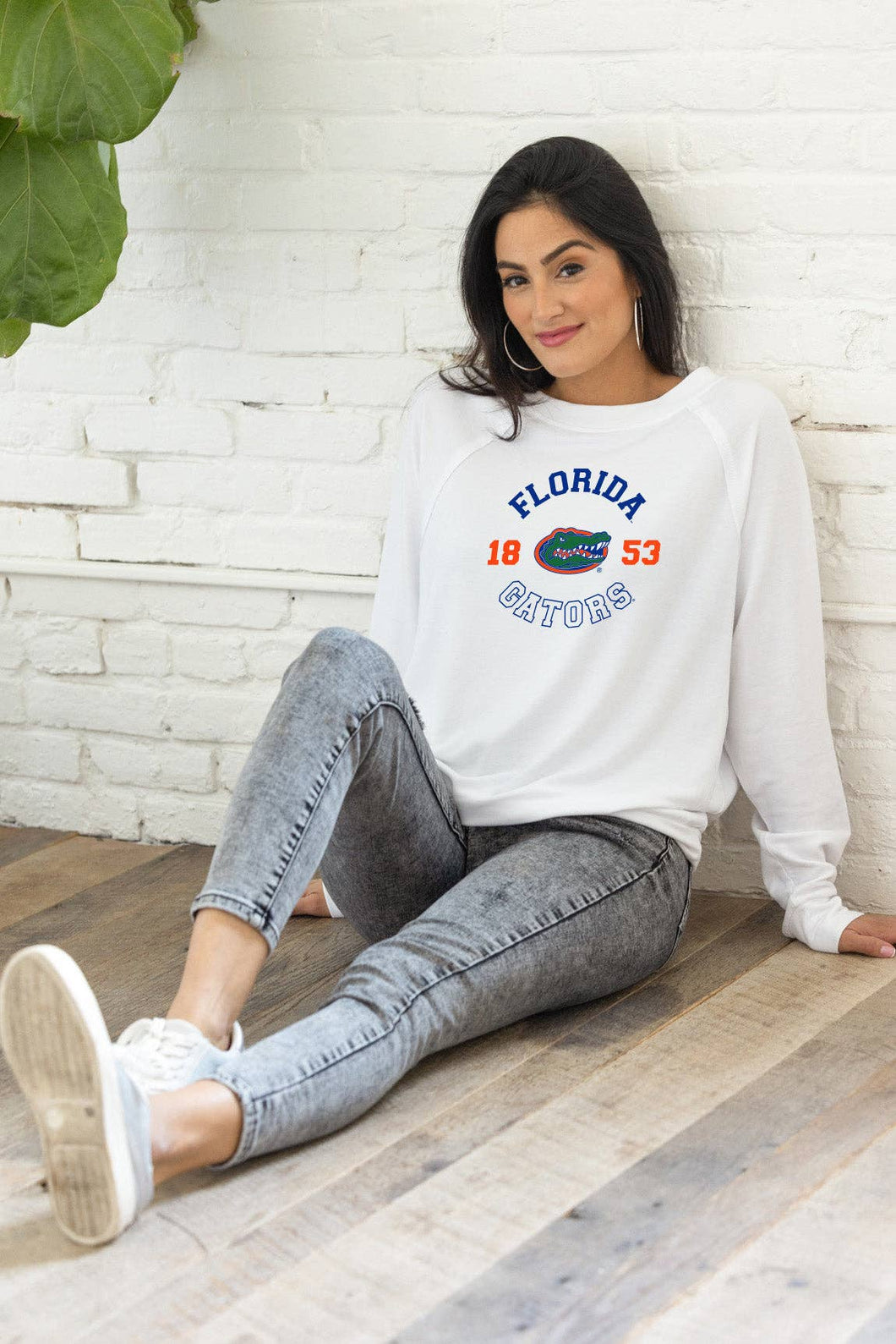 woman sitting on the floor wearing a Florida gators long sleeve white shirt