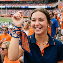Load image into Gallery viewer, Gator fan in the stadium with the Skinny Scarf tired around her wrist and a bracelet 
