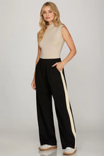 Load image into Gallery viewer, woman wearing black pants with a cream colored accents along the side of the pants paired with a cream top
