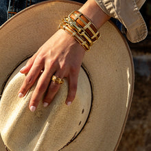 Load image into Gallery viewer, person wearing Capucine de Wulf Horsehead Hinged Bangle paired with other gold jewelry 
