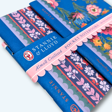 Load image into Gallery viewer, two small notebooks with blue and pink floral covers side view showing the staple binding 
