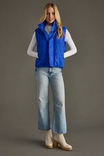 Load image into Gallery viewer, woman in a puffy Classic royal blue Vest paired with a black shirt and jeans with her hands in the bvest pockets
