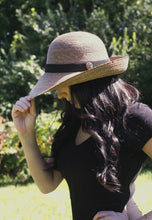 Load image into Gallery viewer, woman wearing the Chloe Hand-woven Palm Hat holding the brim

