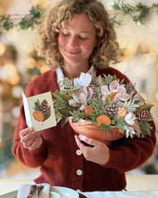 Load image into Gallery viewer, person reading the card that comes with the FreshCut Paper Winter Magnolia Greeting Card
