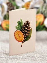 Load image into Gallery viewer, close up of a card with a pine cone and an orange slice 
