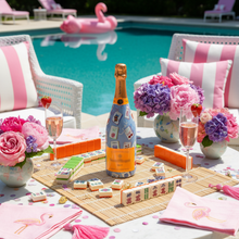 Load image into Gallery viewer, Champagne Bottle covered with the Pastel Blue Mahjong Champagne Bottle Wrap on a table set by a pool
