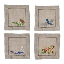 Load image into Gallery viewer, four tan napkins each with a different embroidered design, a pine cone, mushroom and berries, feathers, and leaves, berry and acorns 
