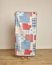 Load image into Gallery viewer, person holding up a towel made from a patchwork of cream, blue and red prints
