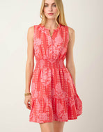 person wearing a pink dress with pale pink print, ruffle neckline, rushed waistline and flounced hem 