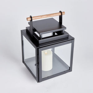 black metal lantern with glass sides and wood handle on the top of the lantern