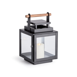 black metal lantern with glass sides and wood handle on the top of the lantern